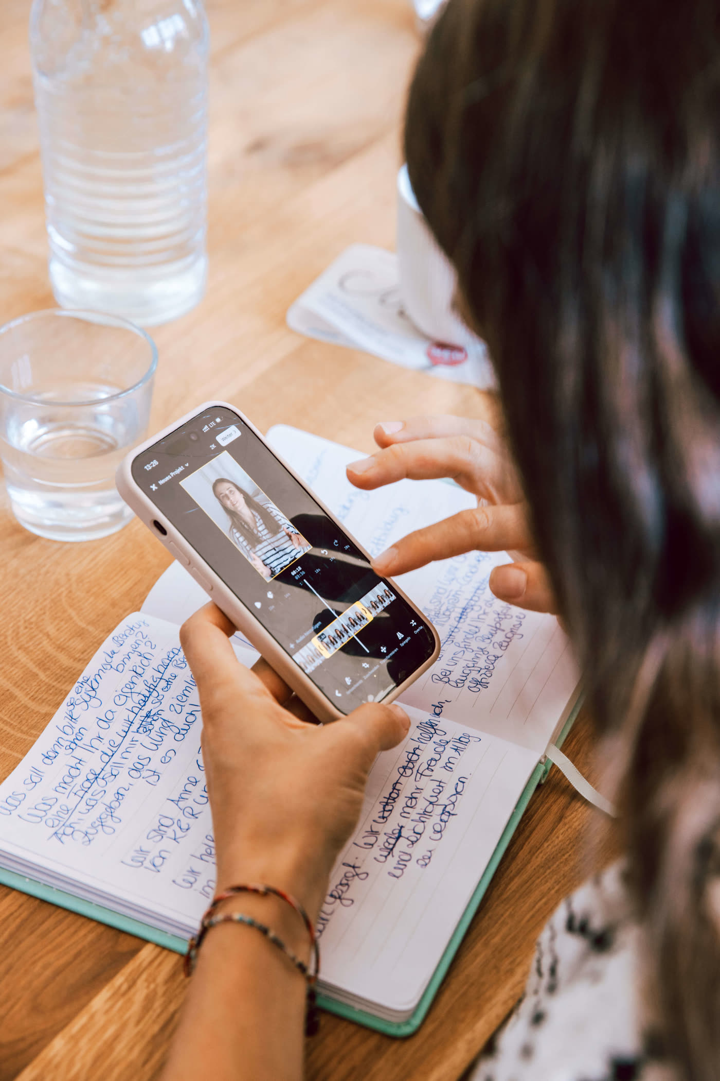 Teilnehmerin schneidet ein Video am Handy, daneben ihre handschriftlichen Notizen